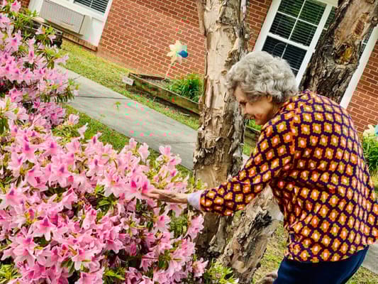 A resident engaging with flowers in the garden