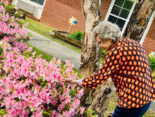A resident engaging with flowers in the garden