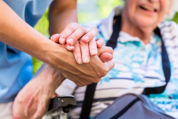 Caregiver holding the hand of an elderly resident
