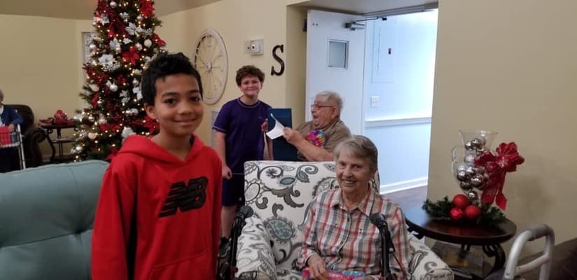 Residents and a child celebrating with gifts near a Christmas tree