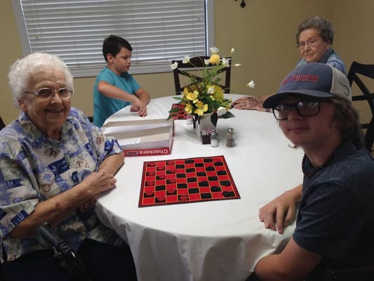 Residents playing checkers with a young visitor