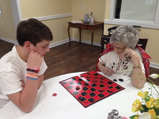 A young boy and an elderly woman playing checkers.