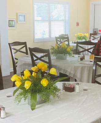 Dining room with yellow flowers and tables set up