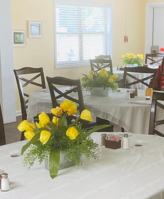 Dining room with yellow flowers and tables set up