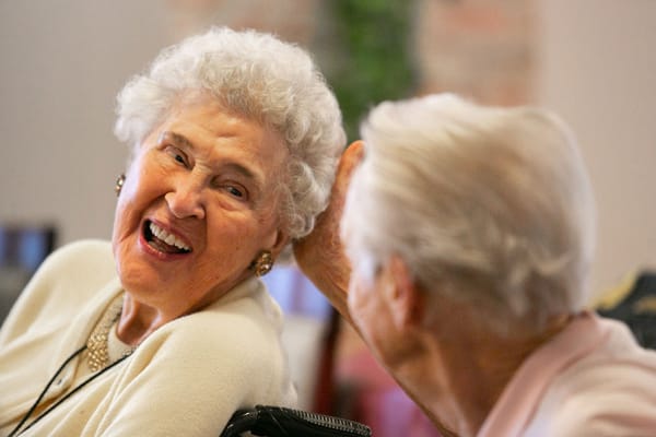 Two seniors sharing a joyful moment in a common area