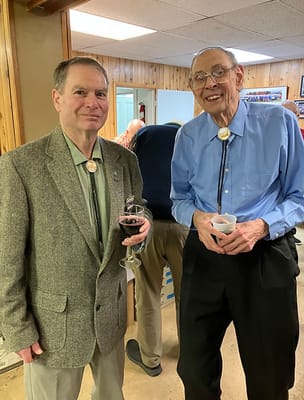 Two elderly men in a social setting with drinks