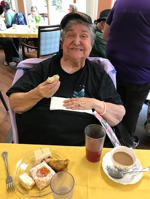 Smiling resident enjoying cake in a communal dining area