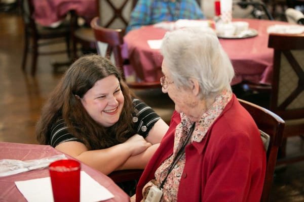 A young girl interacting with an elderly woman in a cozy common area