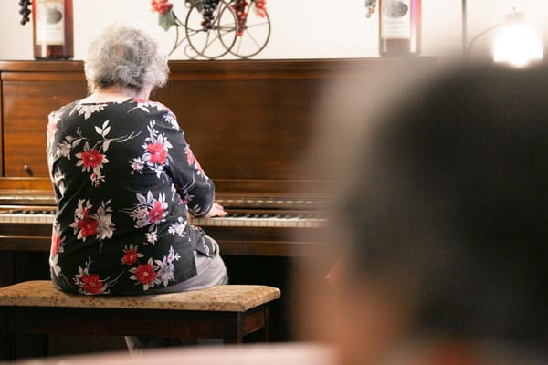 Resident playing piano in an activity room