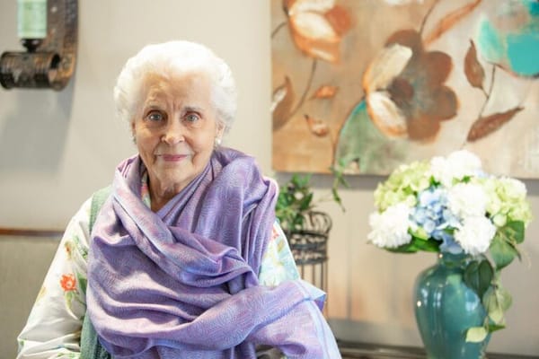 An elderly woman smiling in a colorful interior