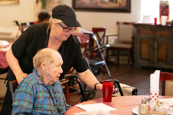 Staff assisting a resident at a dining table