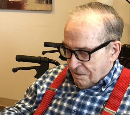 A resident sitting in a chair, wearing glasses