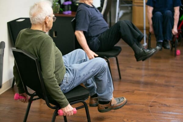 Residents exercising with weights in an activity room