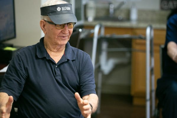 A senior wearing a visor, actively engaged in conversation