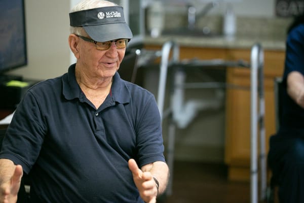 A senior wearing a visor, actively engaged in conversation