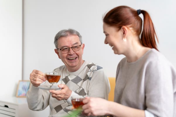 Senior resident enjoying tea with a staff member