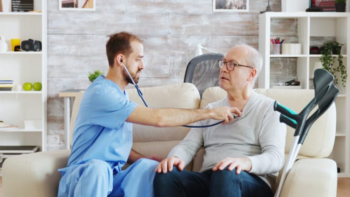 Healthcare professional examining a senior man in a cozy living area