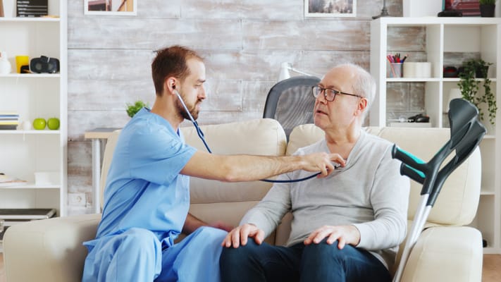 Healthcare professional examining a senior man in a cozy living area