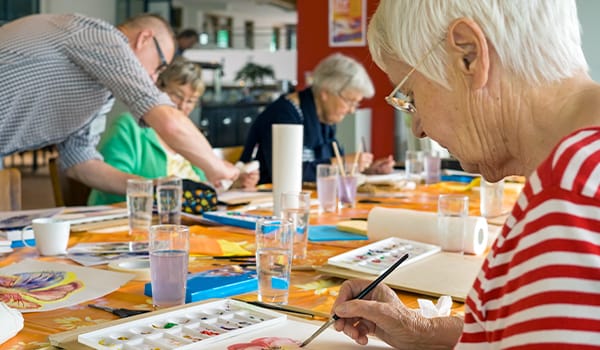 Residents engaging in a painting activity at a communal table
