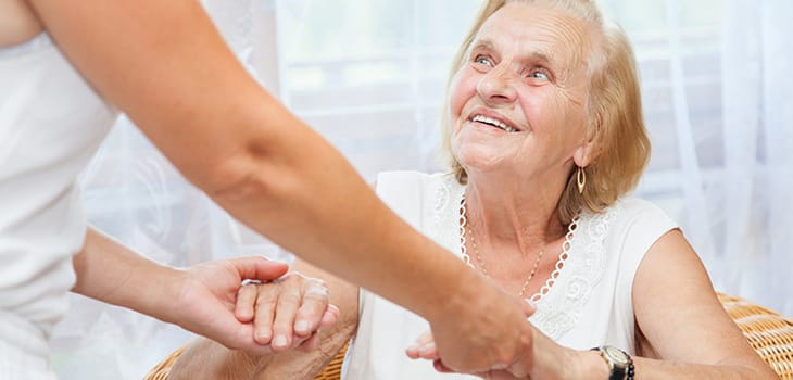 A caregiver holding hands with a smiling resident