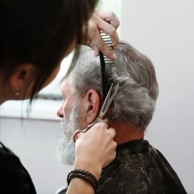A stylist cutting a man's hair in a salon