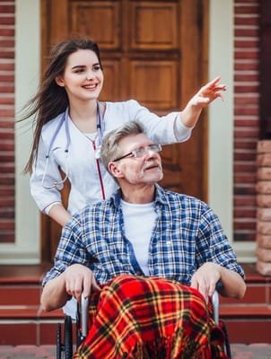 A nurse assisting a resident in a wheelchair outdoors