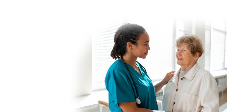 A caregiver interacting with a senior resident in a bright interior setting