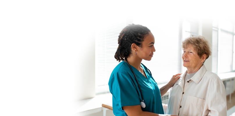 A caregiver interacting with a senior resident in a bright interior setting