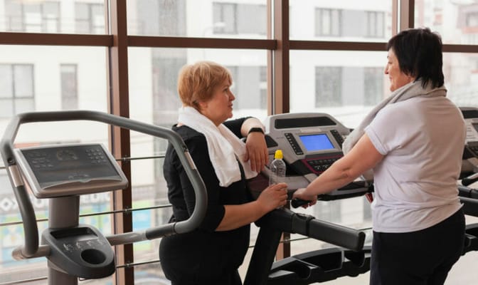 Two women engaging in conversation while exercising