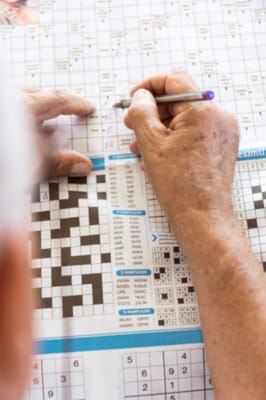 Close-up of hands completing a crossword puzzle