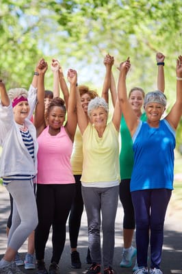 Group of women celebrating with raised arms outdoors