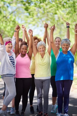 Group of women celebrating with raised arms outdoors