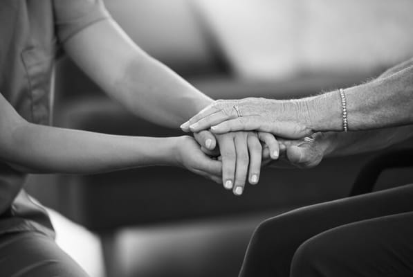Caregiver and resident holding hands in a supportive gesture