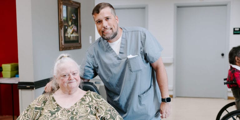Staff member posing with a resident in a facility common area
