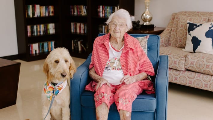 Senior resident sitting with a dog in a common area