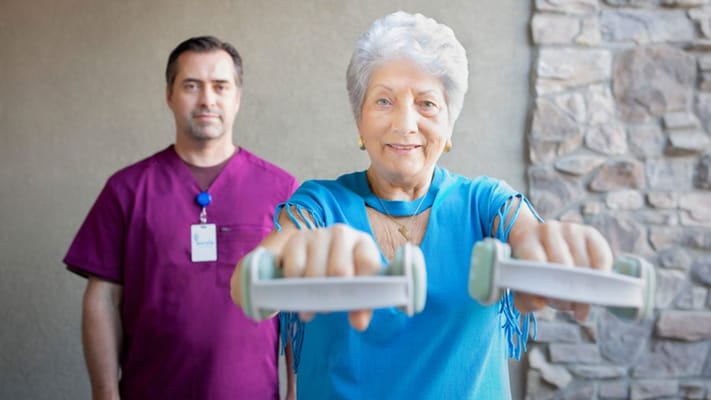 Senior resident exercising with a staff member assisting