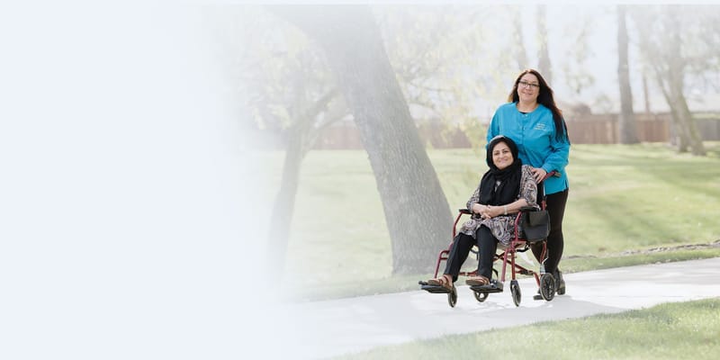 Staff member assisting a resident in a wheelchair outdoors