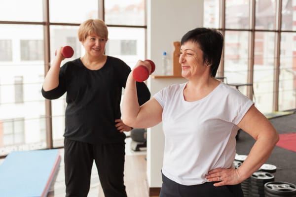 Residents exercising with dumbbells in a bright fitness room