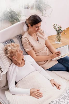 Caregiver reading to an elderly resident in a cozy room