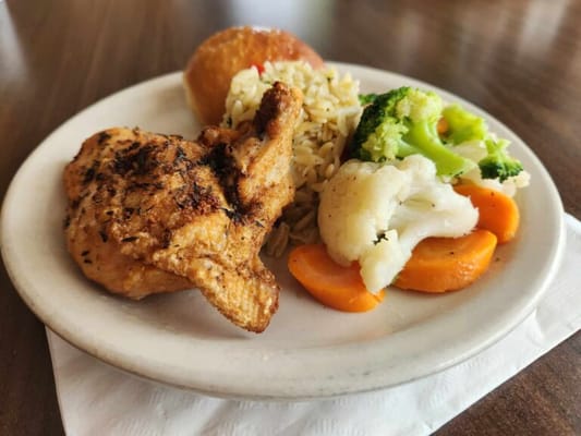 A plate of chicken, rice, and vegetables served for a meal