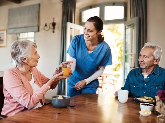 Caregiver serving juice to residents in a dining area