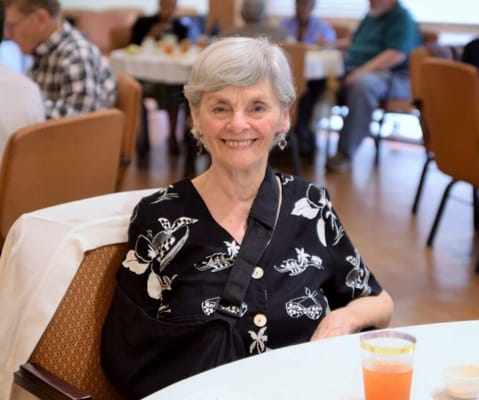 Resident smiling in a common area during mealtime