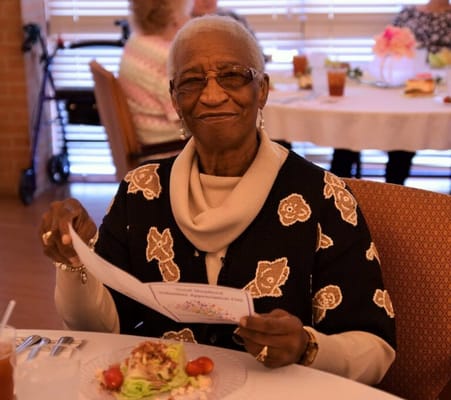 Resident enjoying a meal and reading a menu