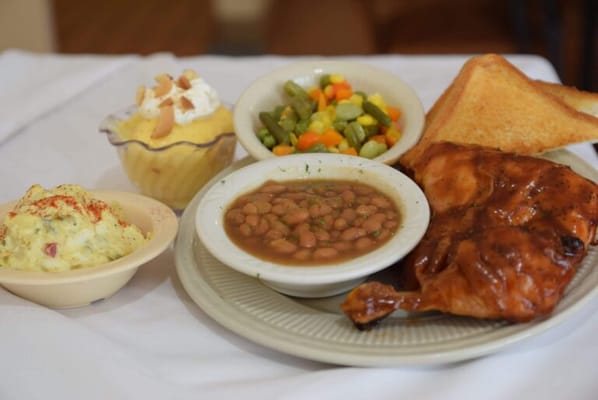 A plated meal featuring chicken, vegetables, and dessert
