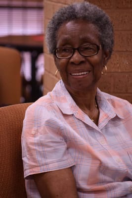 An elderly woman smiling in a cozy environment