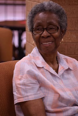 An elderly woman smiling in a cozy environment