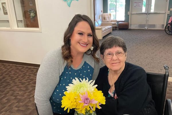 Staff member with a resident and a bouquet of flowers