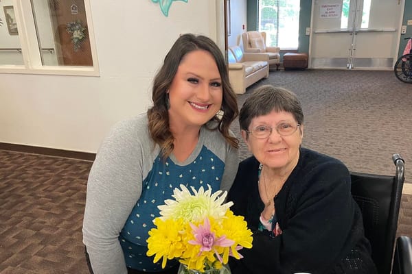 Staff member with a resident and a bouquet of flowers