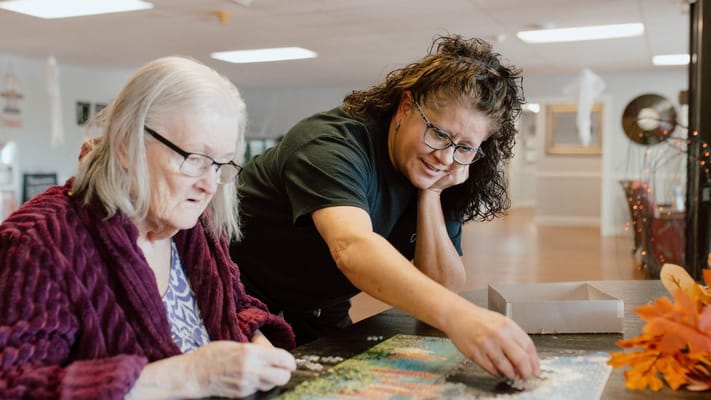Resident and staff member working on a puzzle together