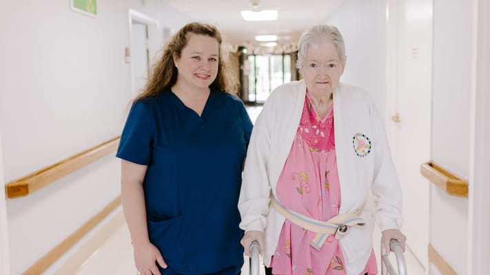 A staff member assisting a resident in a corridor